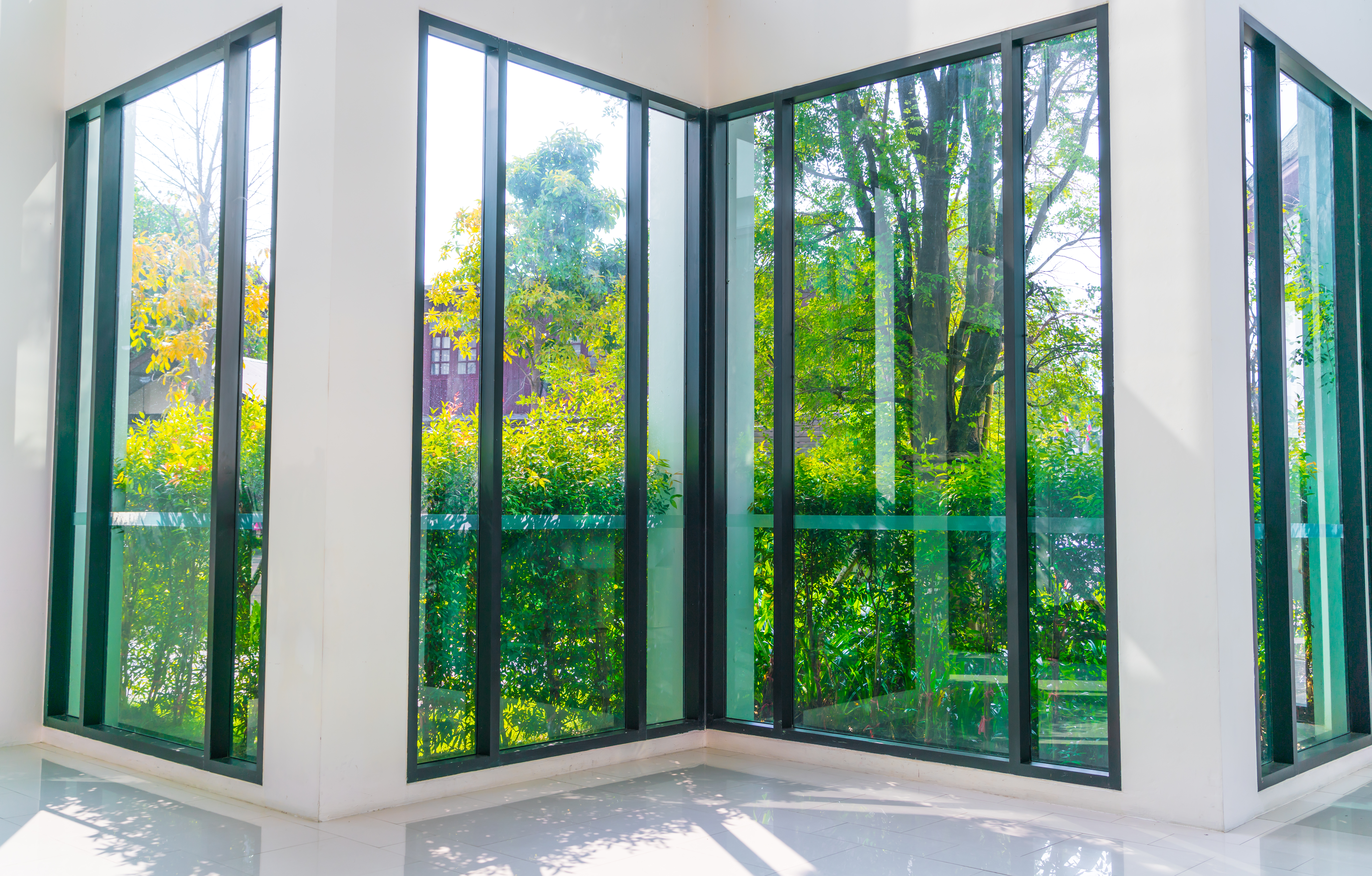 Fenêtre en verre donnant à un jardin vert